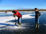 Art drilt een gat in het ijs om door te vissen